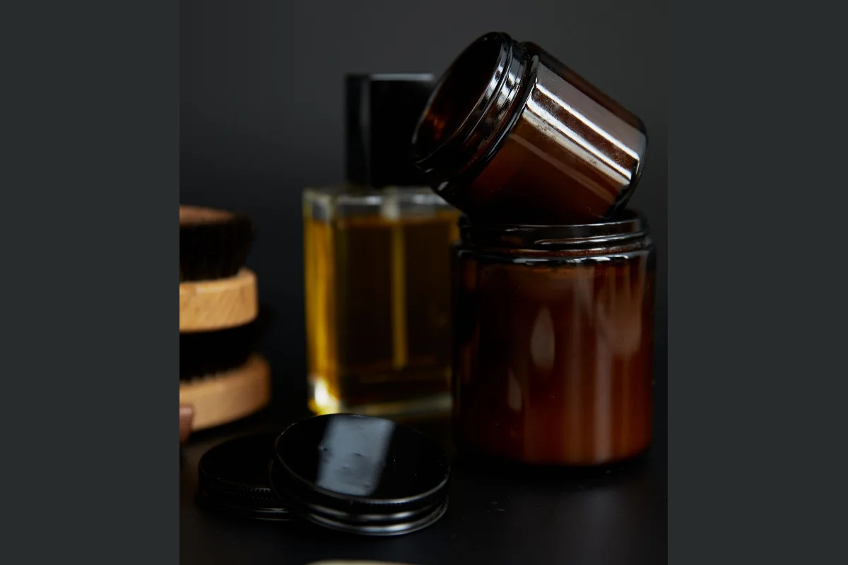 Open amber glass jars and black lids on a dark tabletop