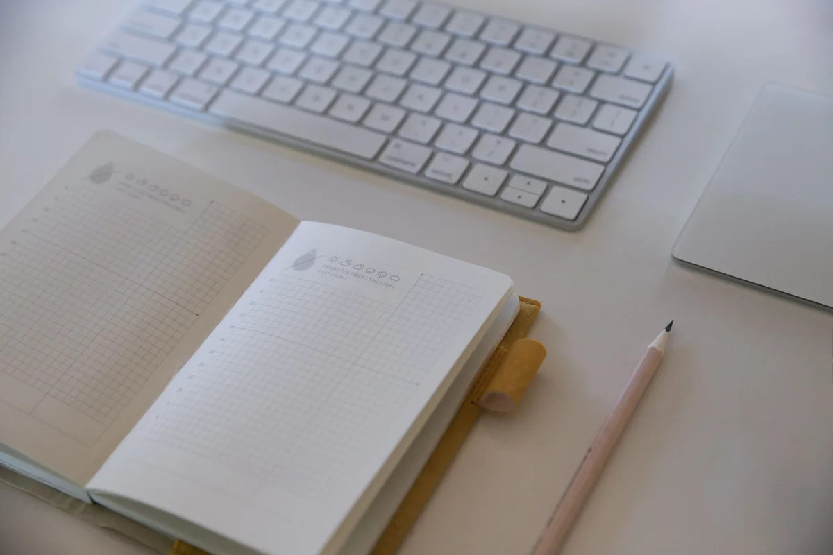 Open notebook and pencil beside a keyboard on a desk