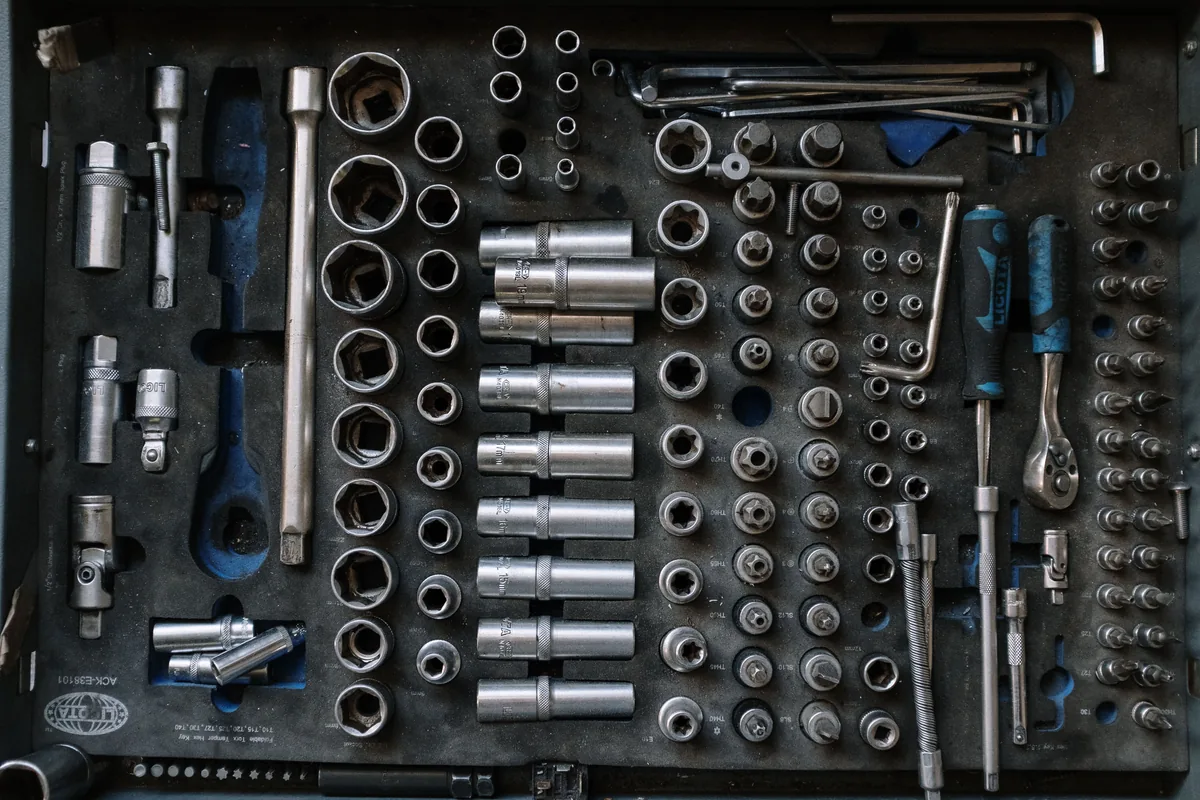 Flat lay of wrenches, sockets and hand tools arranged on a workshop surface