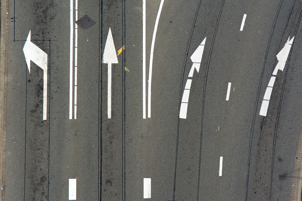 White directional arrows and lane markings painted on an asphalt road